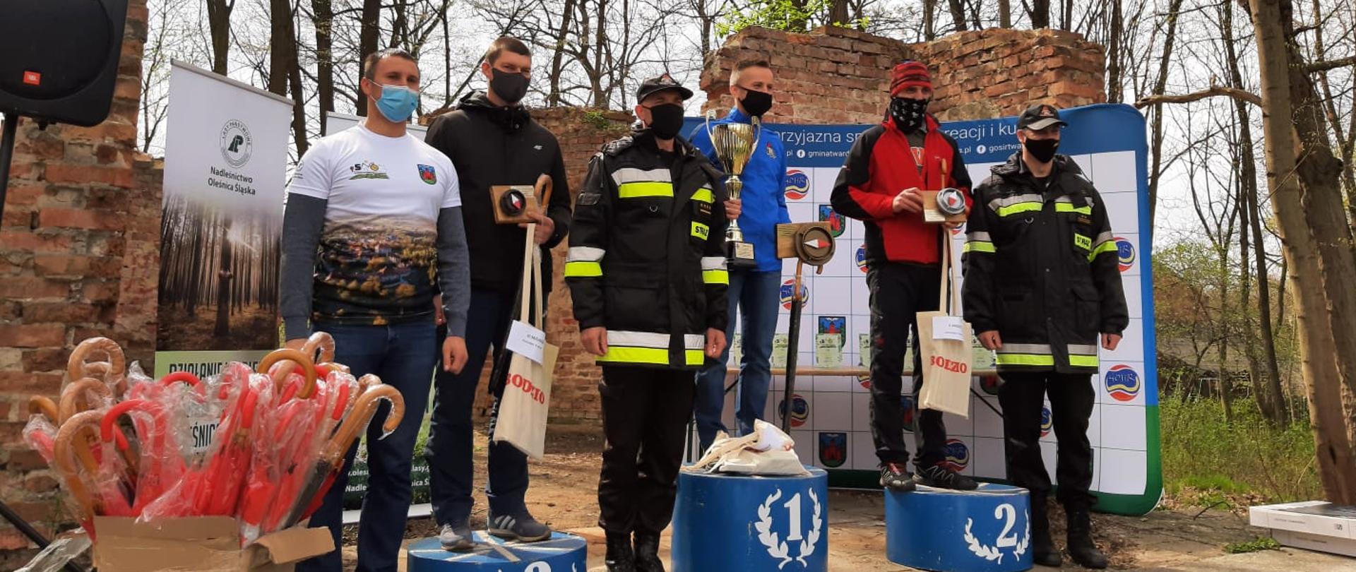 Biegacze oraz strażacy stoją na podium.