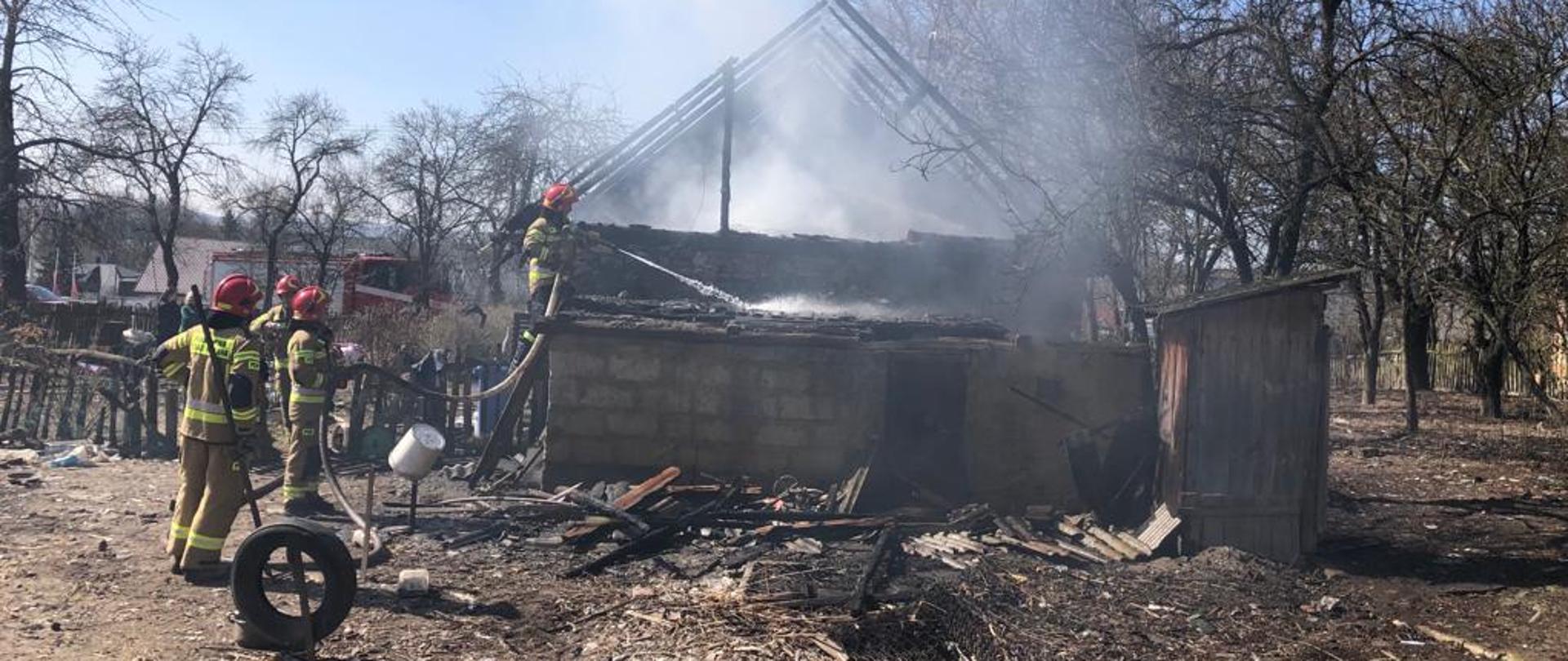 Na miejscu widoczny pożar domu jednorodzinnego gaszony prze strażaków z drabiny przystawnej