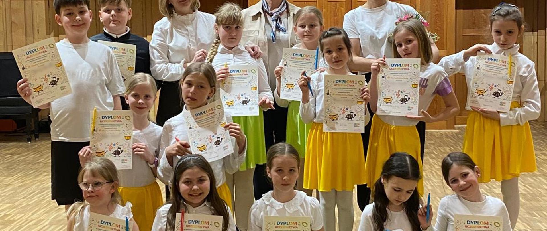 Grupa dzieci w strojach na scenie sali koncertowej