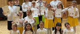 Grupa dzieci w strojach na scenie sali koncertowej