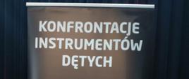 Napis na ciemnym tle z tekstem "Konfrontacje Instrumentów Dętych"