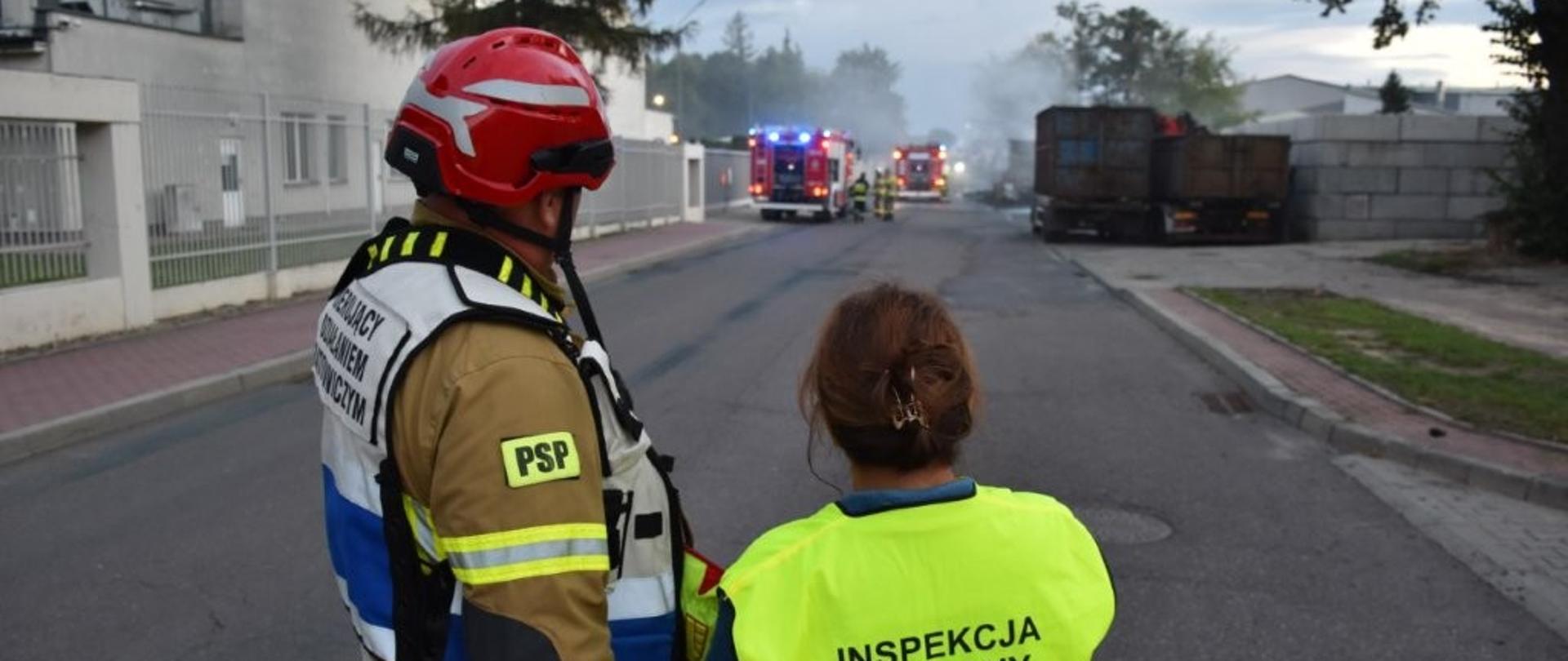 Strażak i Inspektor Ochrony Środowiska obserwują akcję gaśniczą