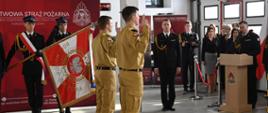 Strażacy składają ślubowanie komendantowi powiatowemu który z mównicy prowadzi uroczystość, w tle sztandar oraz pododdziały