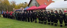 Przedstawiciele jednostek Ochotniczych Straży Pożarnych uczestniczą w uroczystym apelu zorganizowanym podczas wydarzenia strażackiego. W zbiórce biorą udział poczty sztandarowe, druhowie w mundurach wyjściowych oraz członkowie Młodzieżowych Drużyn Pożarniczych.