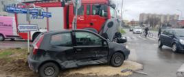 Skrzyżowanie ruchliwych ulic. Uszkodzony z prawej strony Fiat Punto, z nim samochód gaśniczy.