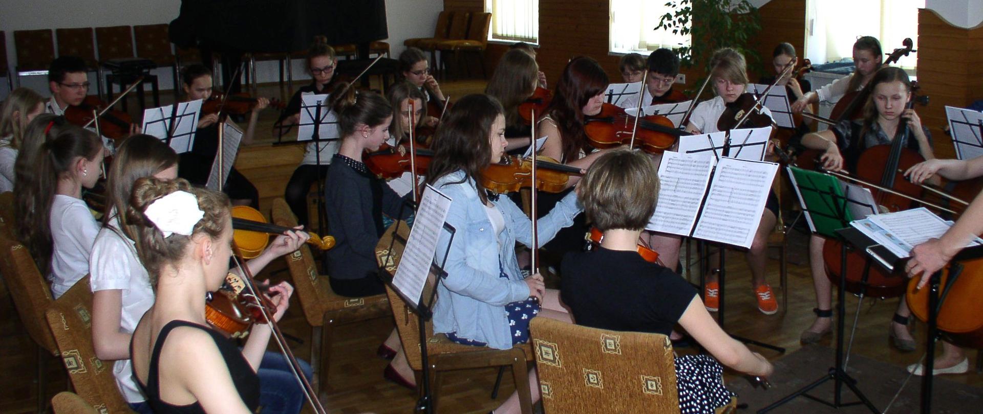 Uczniowie grający w zespole na instrumentach smyczkowych