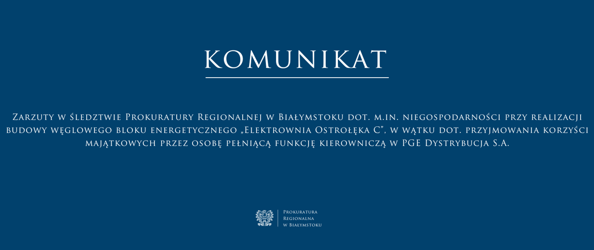 Baner ma ciemnoniebieskie tło i biały tekst, utrzymany w eleganckiej, klasycznej czcionce. W górnej części znajduje się duży napis „KOMUNIKAT” podkreślony cienką białą linią. Poniżej umieszczono treśc komunikatu „Zarzuty w śledztwie Prokuratury Regionalnej w Białymstoku dot. m.in. niegospodarności przy realizacji budowy węglowego bloku energetycznego „Elektrownia Ostrołęka C”, w wątku dot. przyjmowania korzyści majątkowych przez osobę pełniącą funkcję kierowniczą w PGE Dystrybucja S.A.” Na dole, pośrodku, znajduje się logo Prokuratury Regionalnej w Białymstoku oraz jej nazwa.