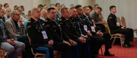Na zdjęciu widzimy uczestników konferencji a w pierwszym rzędzie siedzą generałowie PSP słuchający wykładu w sali konferencyjnej. 