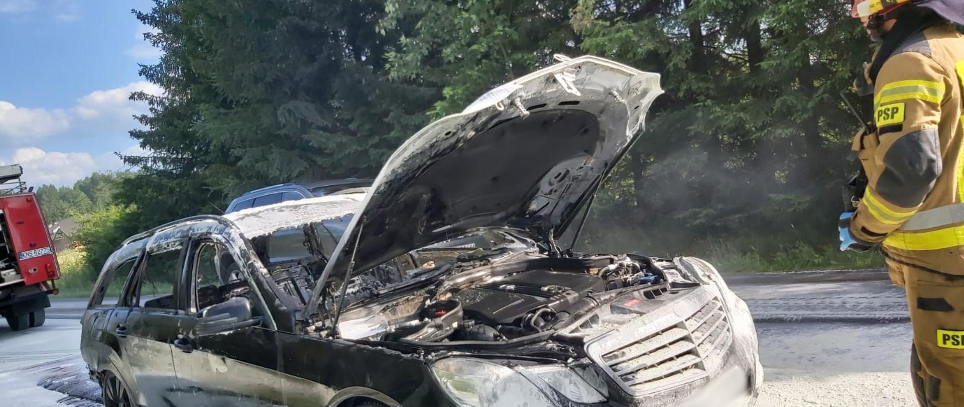 Spalony samochód a obok strażak