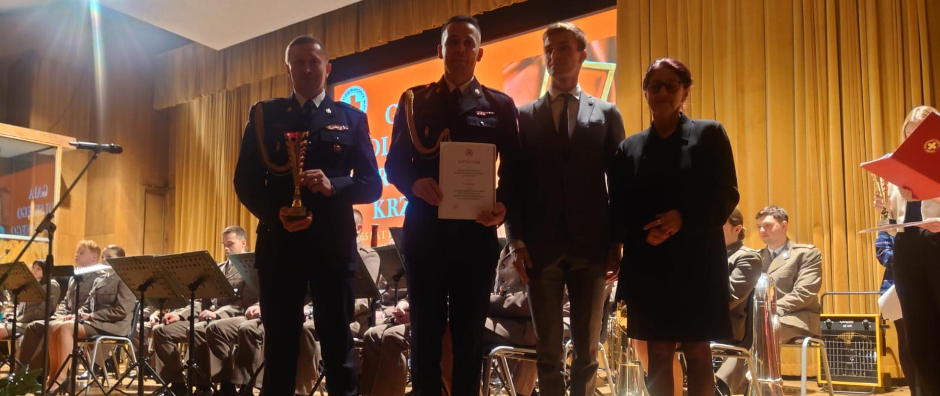 Na zdjęciu widoczni w auli Akademii Wychowania Fizycznego w Krakowie odbierający i wręczający Puchar i dyplom za zajęcie drugiego miejsca w programie pn. "Strażacy w Honorowym Krwiodawstwie Ognisty Ratownik - Gorąca Krew" w kategorii "Najaktywniejsza Jednostka PSP" w Małopolsce Komendant Powiatowy Państwowej Straży Pożarnej w Gorlicach wraz Zastępcą Dowódcy Jednostki Ratowniczo-Gaśniczej w Gorlicach i członkami zarządu Małopolskiego Oddziału Okręgowego.