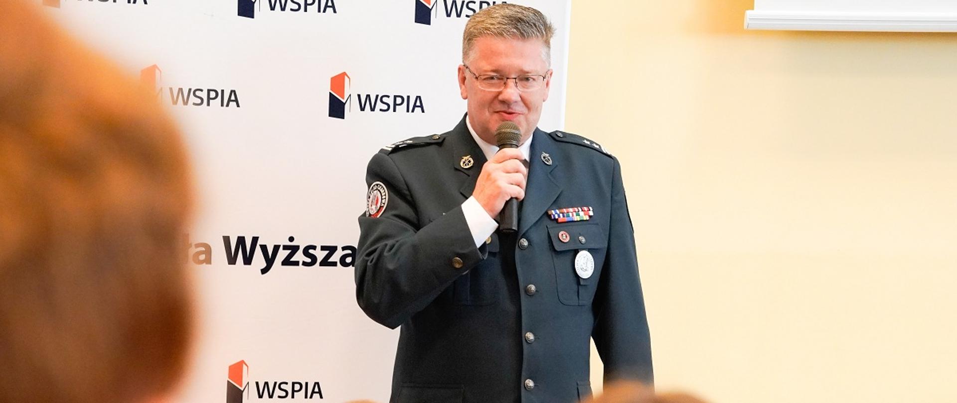 Dyrektor Izby Administracji Skarbowej w Rzeszowie trzyma w ręce mikrofon.