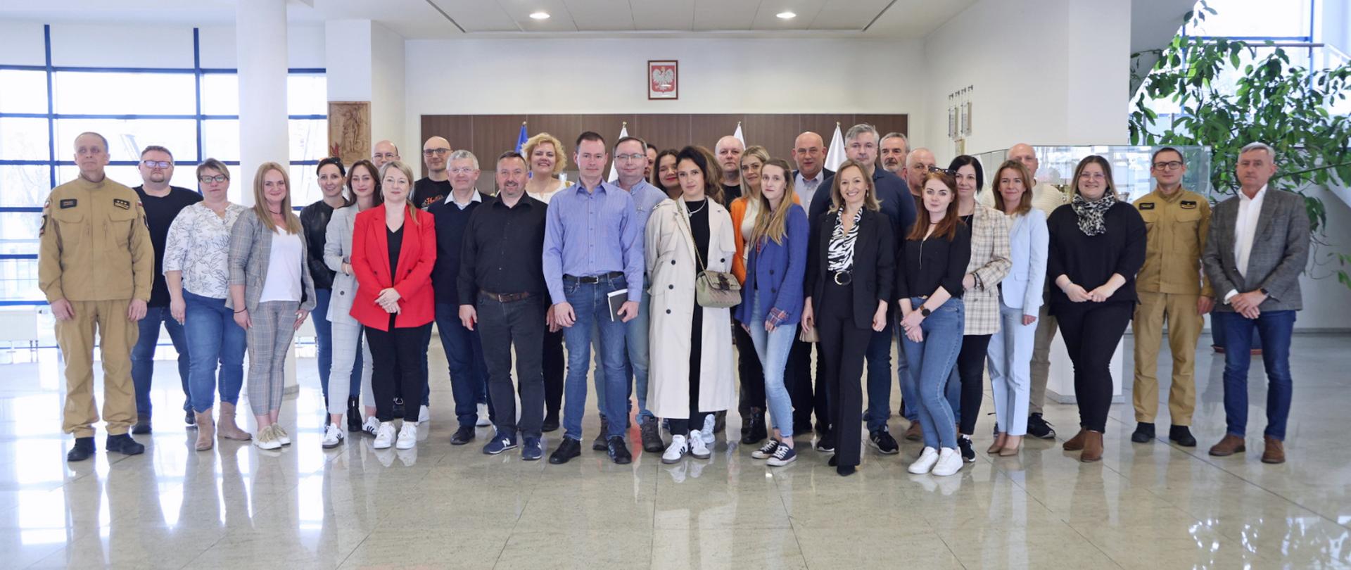 Pamiątkowe zdjęcie grupowe uczestników szkolenia dla inspektorów ochrony przeciwpożarowej (29 osób) w towarzystwie kobiety oraz dwóch oficerów Centralnej Szkoły PSP