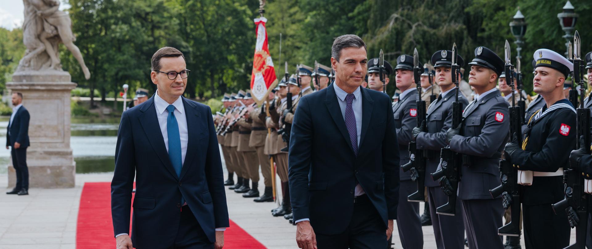 Premier oraz premier Hiszpanii idą, obok stoją żołnierze.