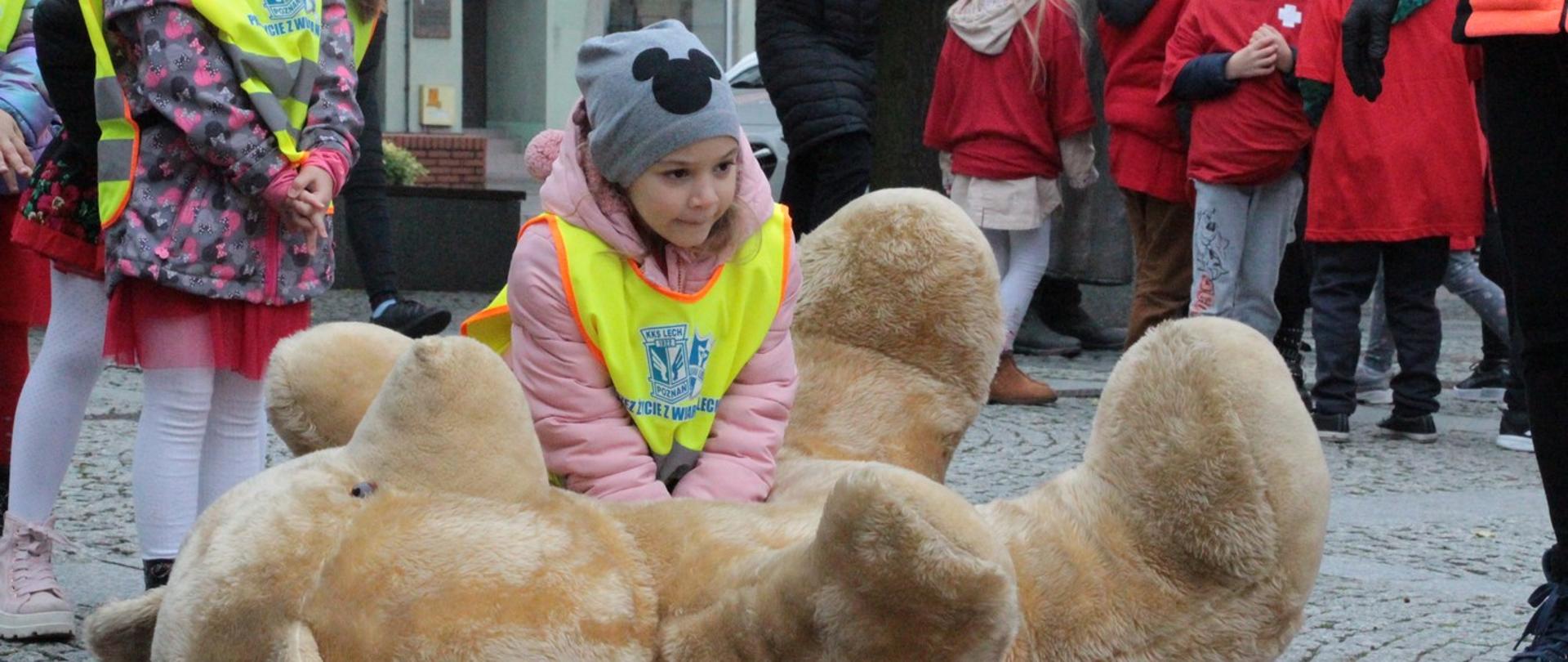 Na zdjęciu dziewczynka biorąca udział w akcji udzielająca pierwszej pomocy misiowi