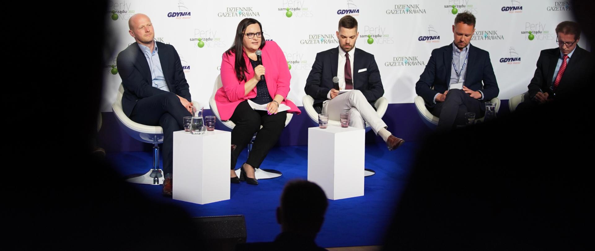 Pięć osób na scenie w fotelach rozmawia w panelu. Wiceminister Małgorzata Jarosińska-Jedynak z mikrofonem.