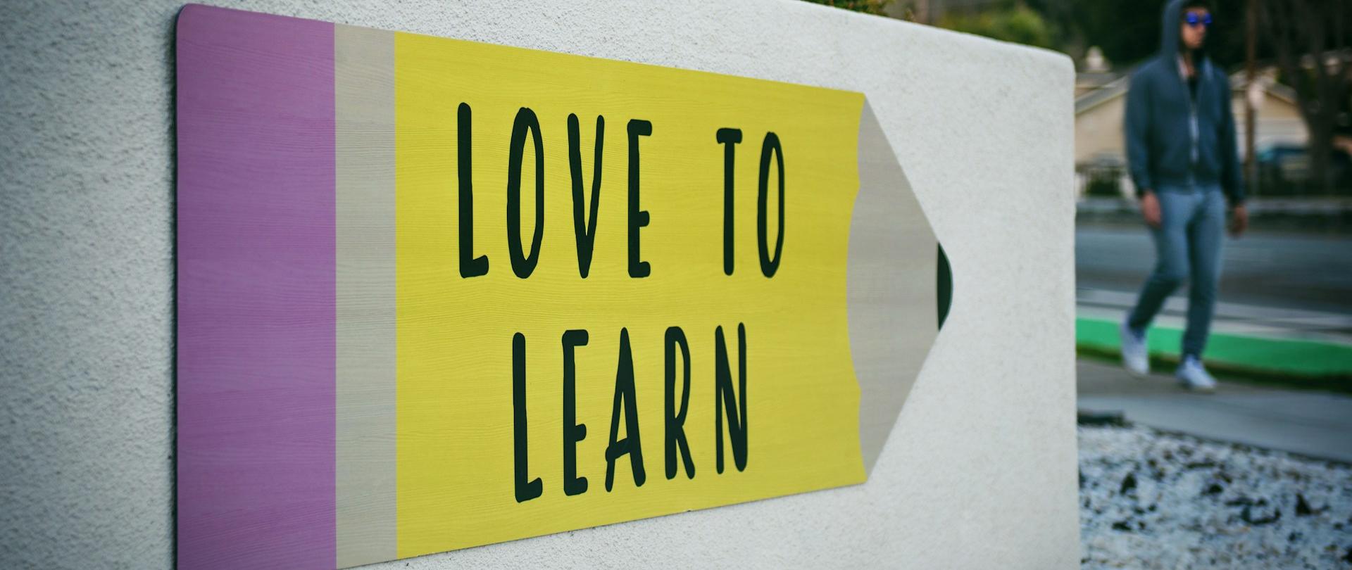 Szyld w kształcie kredki z napisem "LOVE TO LEARN"