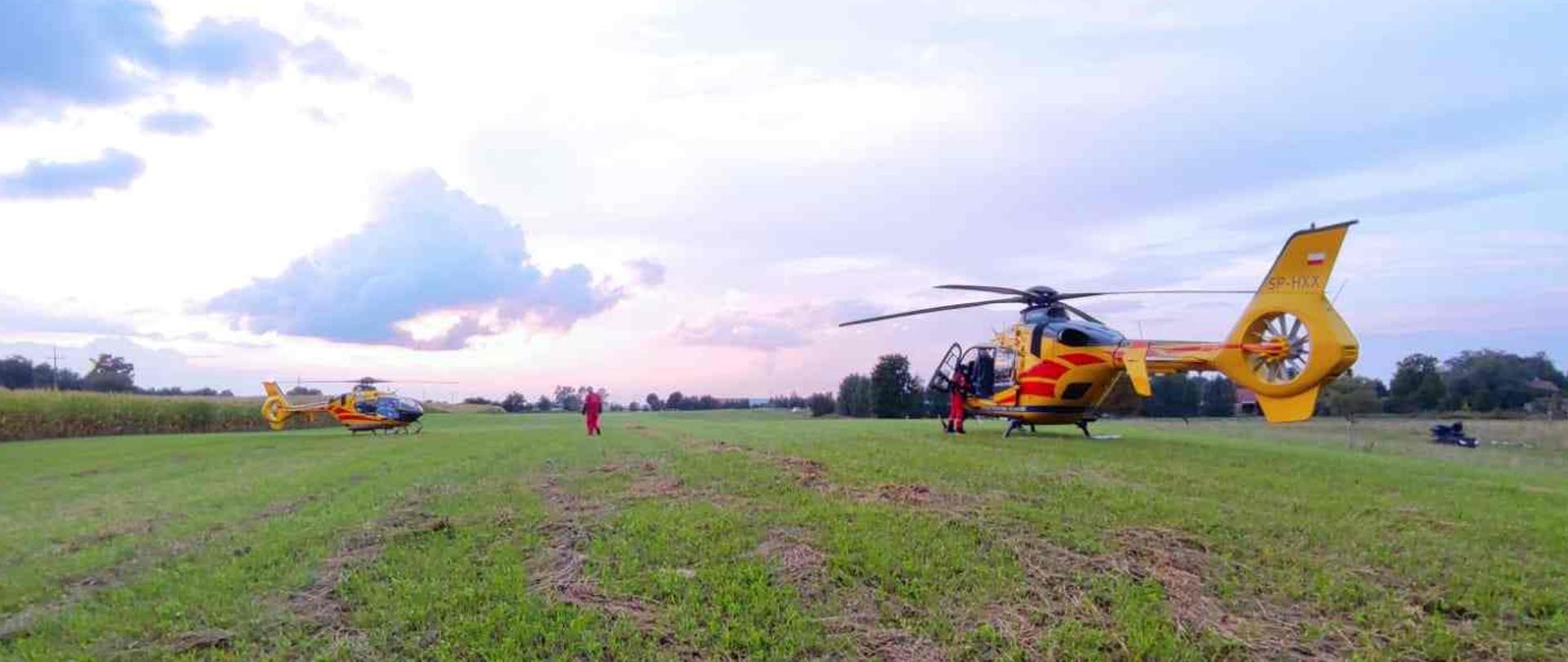 Dwa śmigłowce pogotowia ratunkowego stojące na polu.