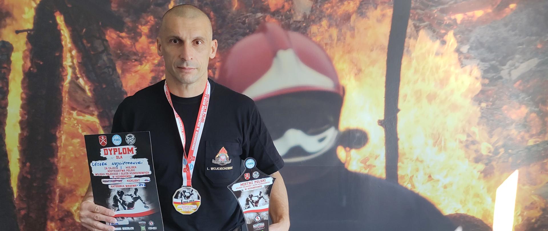 Leszek Wojciechowski Mistrzem Polski w Kickboxingu - strażak stoi wraz z medalem i pucharem