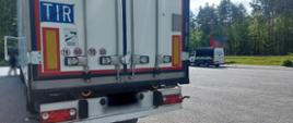 Na pierwszym planie (od lewej): tył naczepy typu chłodnia podpiętej do ciągnika siodłowego. Zestaw stoi w punkcie kontrolnym przy drodze krajowej numer 92 pod Kałuszynem. W tle: oznakowany furgon mazowieckiej Inspekcji Transportu Drogowego.