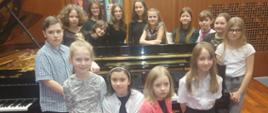 Na zdjęciu 15 uczniów szkoły na scenie sali koncertowej szkoły, po konkursie Młody Wirtuoz.