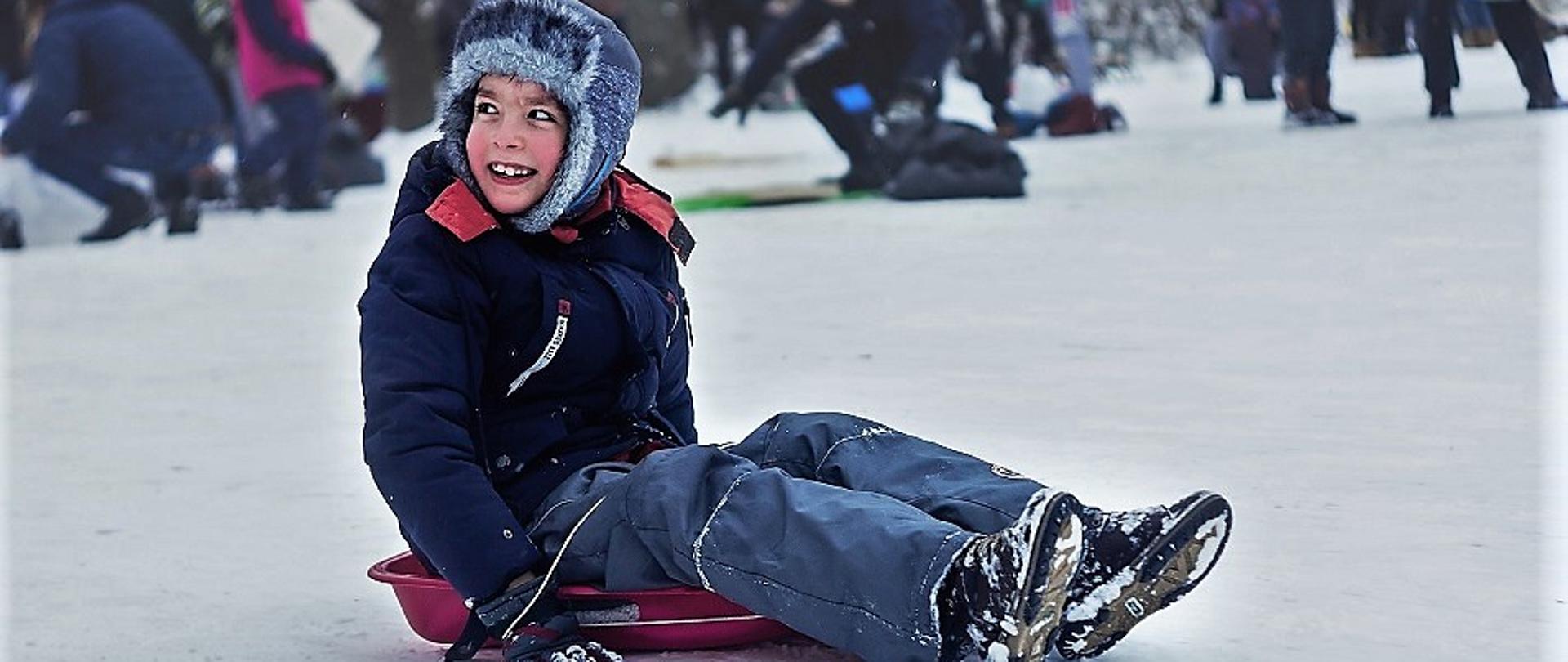 chłopiec na sankach na śniegu