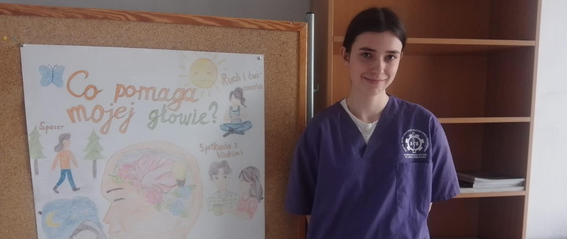 Uczennica Zuzanna Wysocka koło plakatu promującego zdrowe nawyki 