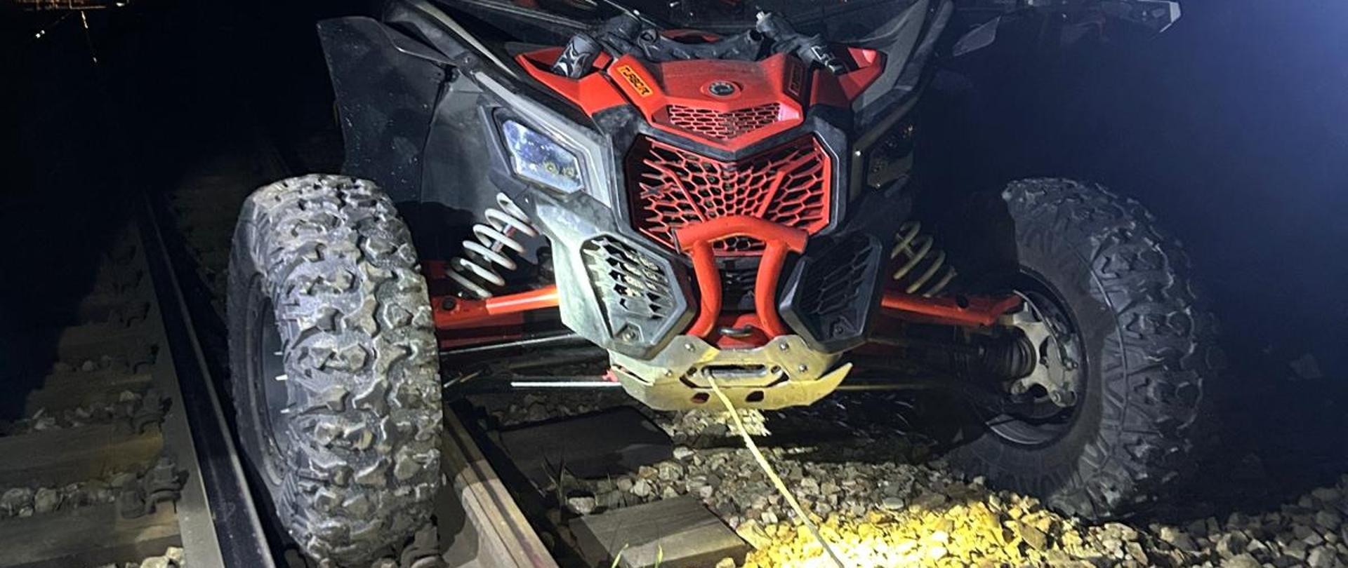 Zdjęcie przedstawia pojazd typu buggy stojący na torowisku z przednim kołem między szynami.