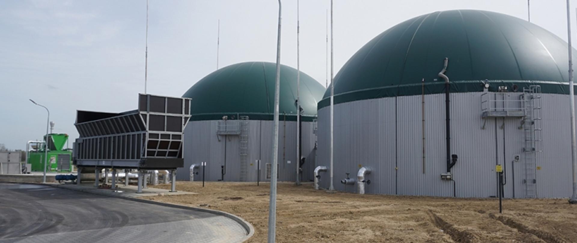 Teren biogazowni. Głównym elementem zdjęcia są dwa obiekty w kształcie walca.