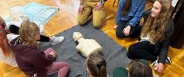 Dzieci w trakcie nauki udzielania pierwszej pomocy. Na pierwszym planie fantom medyczny.