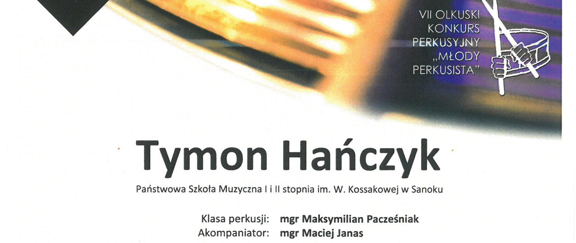 W tle talerz i pałka perkusyjna oraz logo konkursu perkusyjnego w Olkuszu. Czarne litery o treści: dyplom wyróżnienie Tymon Hańczyk, klasa perkusji Maksymilian Pacześniak, akompaniator Maciej Janas, 7 Olkuski Konkurs Perkusyjny Młody Perkusista 