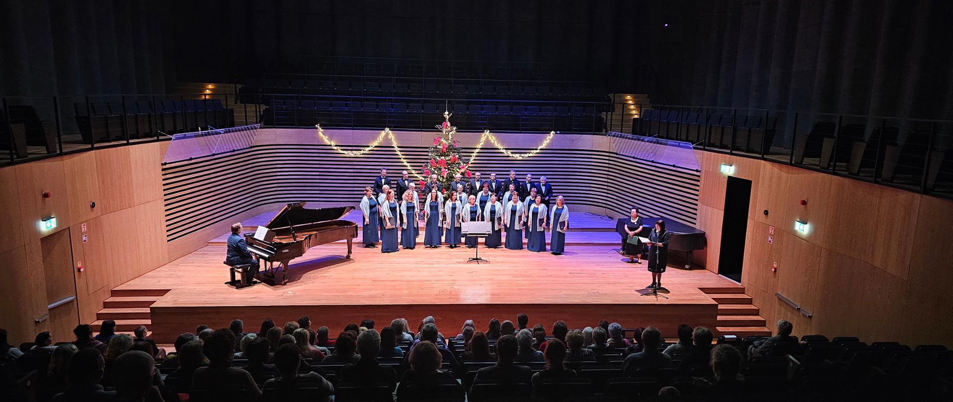 Zdjęcia z Koncertu Kolęd 2024. Występuje Chór "Echo" Zebrzydowice pod batutą Jadwigi Sikory, na fortepianie Arkadiusz Popławski, poezję czyta Pani Beata Sabath. Wszystko na tle Sali koncertowej Państwowej Szkoły Muzycznej w Jastrzębiu-Zdroju