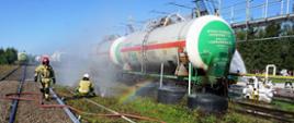 Widoczna cysterna, strażacy rozkładający kurtyny wodne