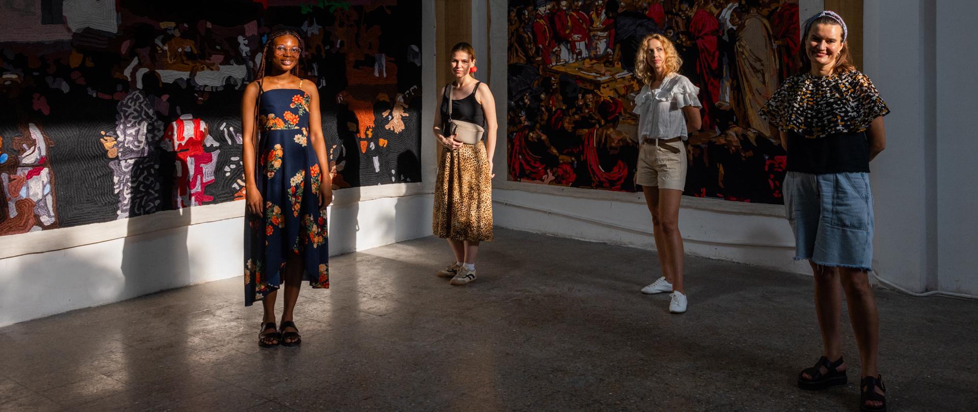 Na tle gobelinów stoją cztery artystki