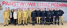 Grupowe zdjęcie strażaków na tle napisu.