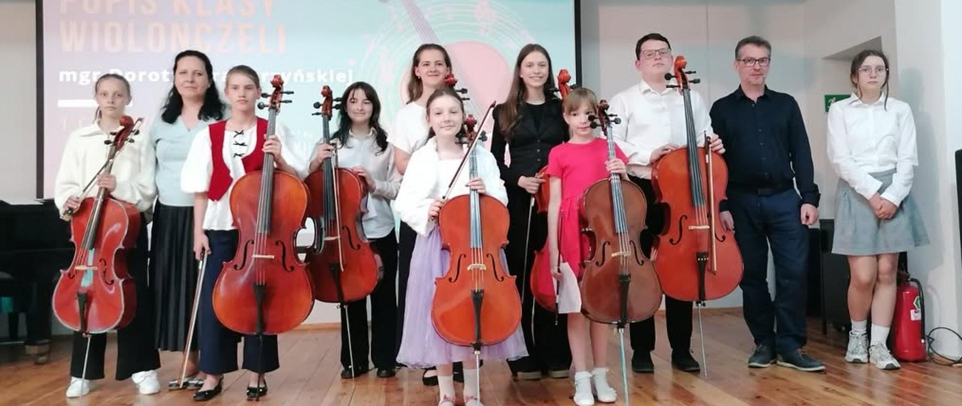 Zdjęcie przedstawiające uczestników popisu klasy wiolonczeli pani Doroty Straburzyńskiej, który odbył się 1 czerwca 2026 r. w auli szkoły.