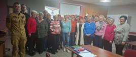 Zdjęcie grupowe na sali wykładowej - dwóch strażaków i seniorzy