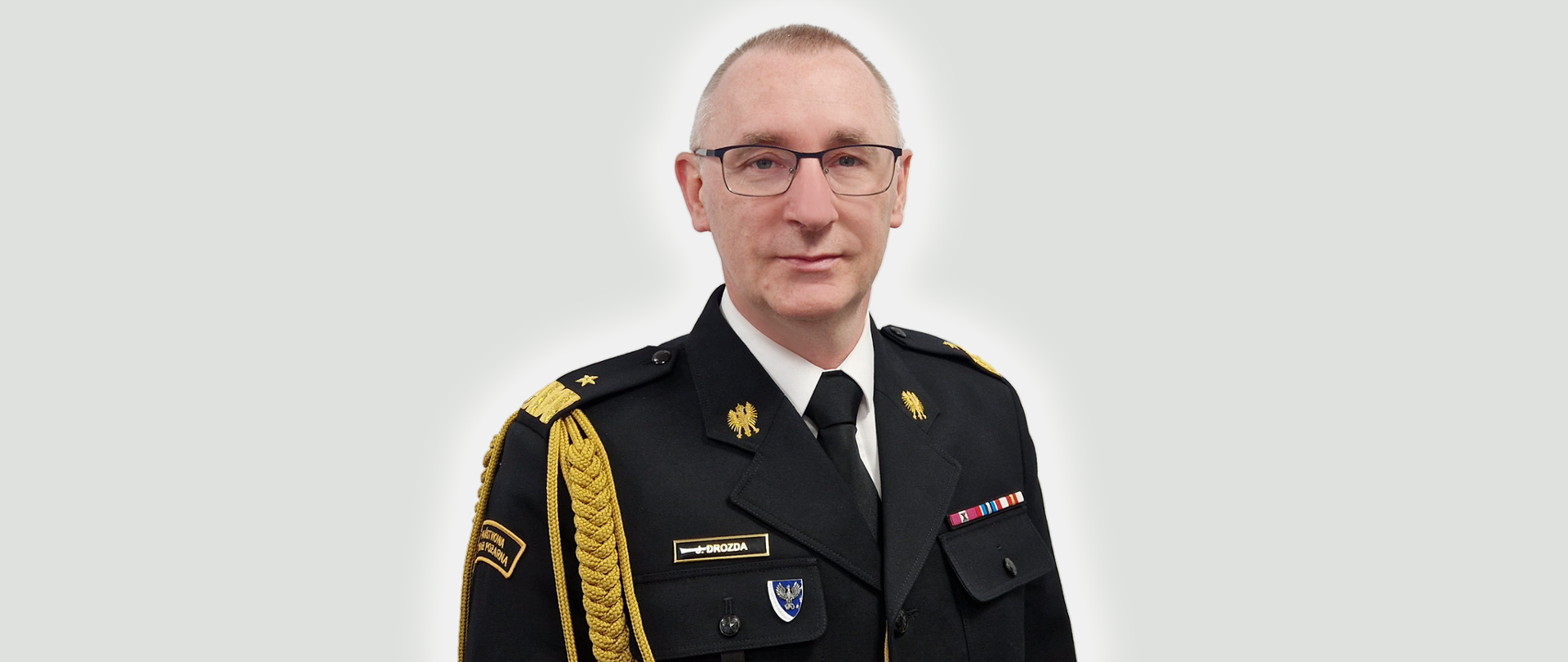 Zdjęcie przedstawia nadbrygadiera Janusza Drozdę Lubuskiego Komendanta Wojewódzkiego PSP w Gorzowie Wlkp.w mundurze na szarym tle.
