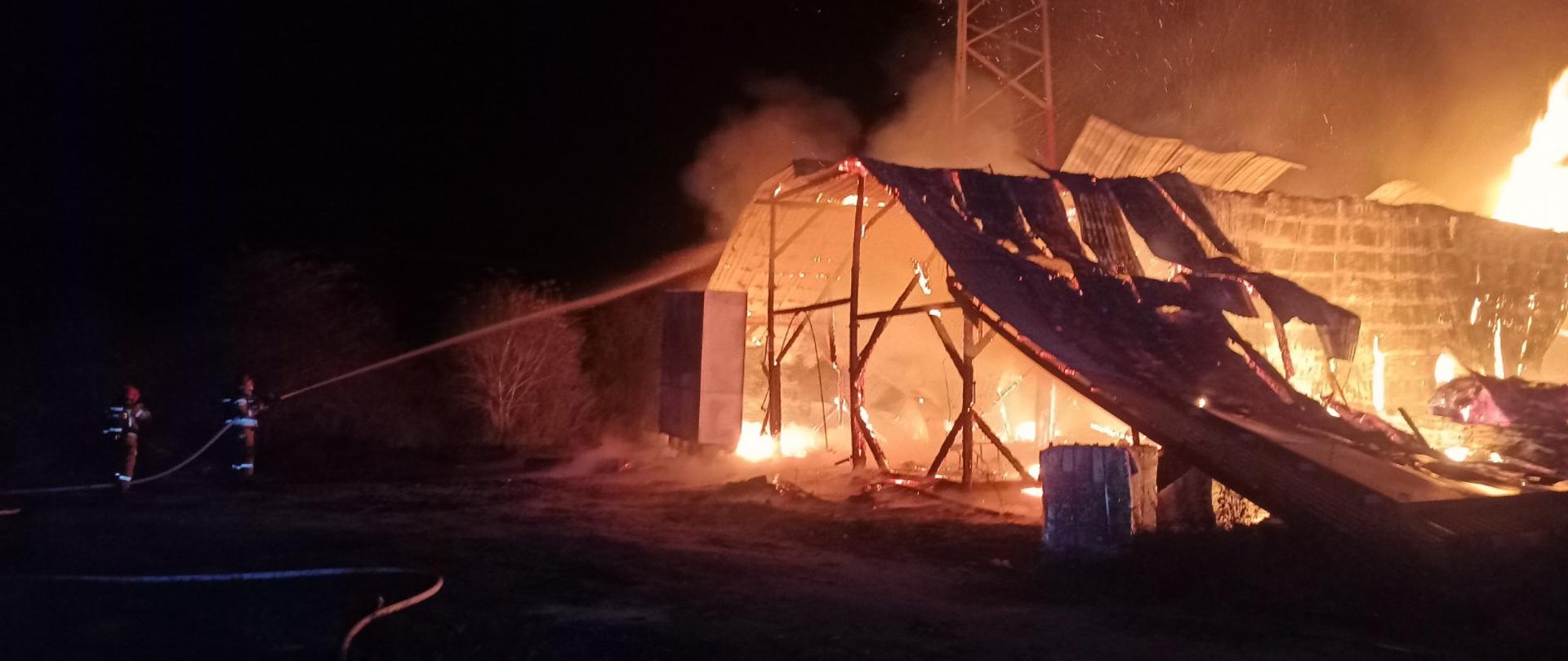 Zdjęcie przedstawia strażaków gaszących budynek objęty pożarem