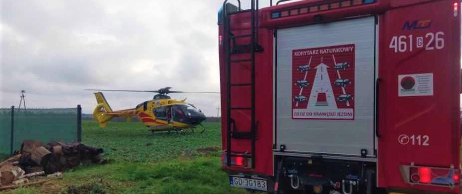 Śmigłowiec stoi na polu przed wozem strażackim