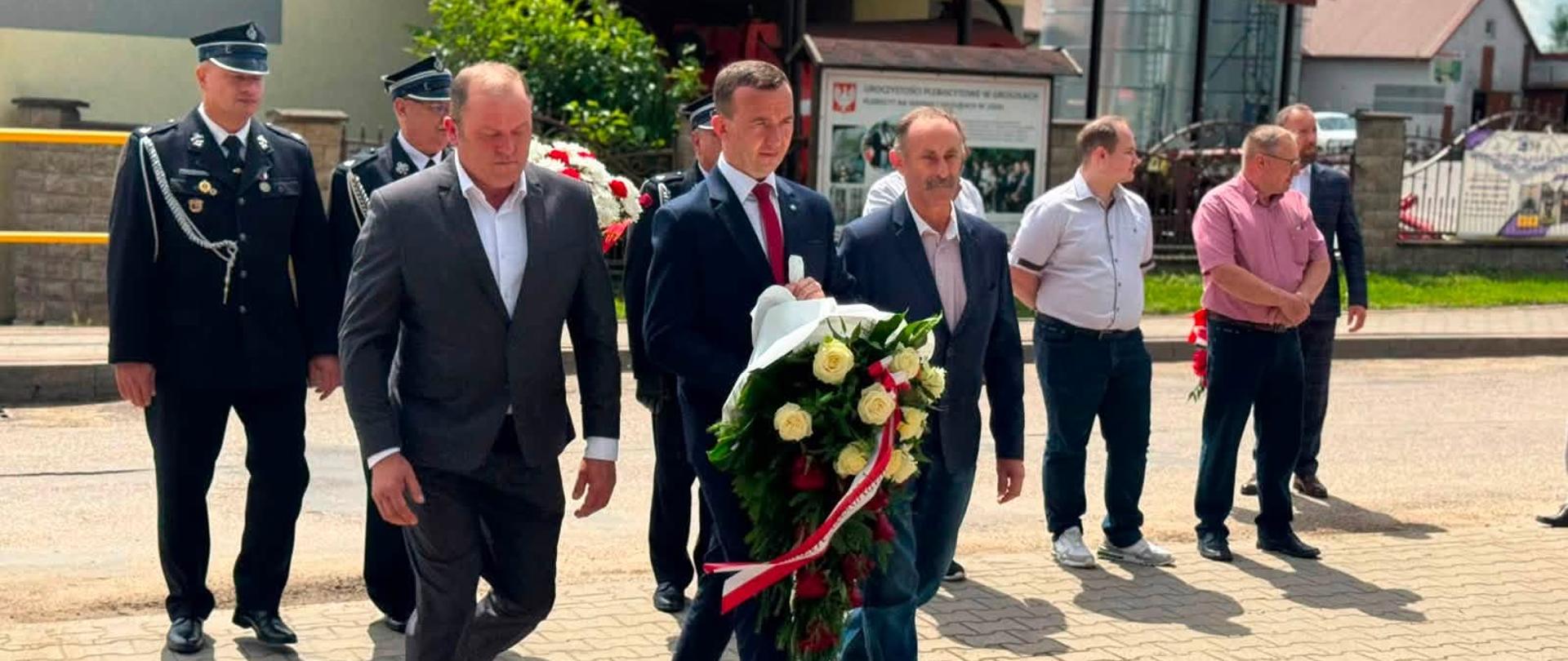 grupa oficjeli, w tym wicewojewoda, składają kwiaty pod pomnikiem