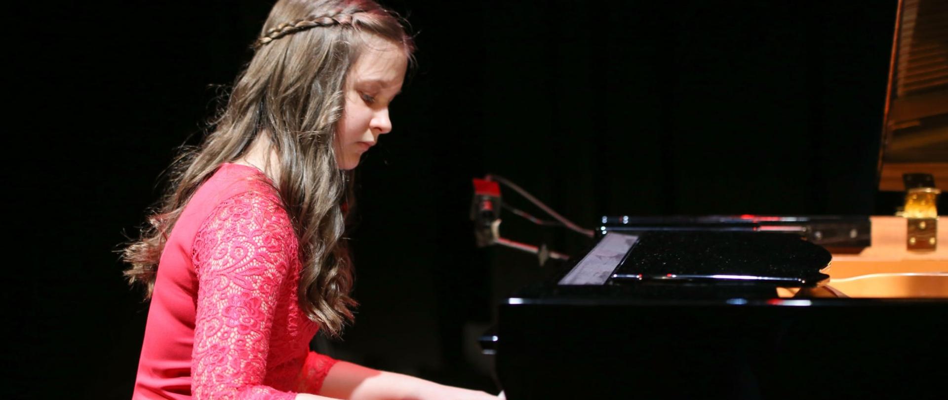 Dziewczynka w różowej sukience gra na fortepianie