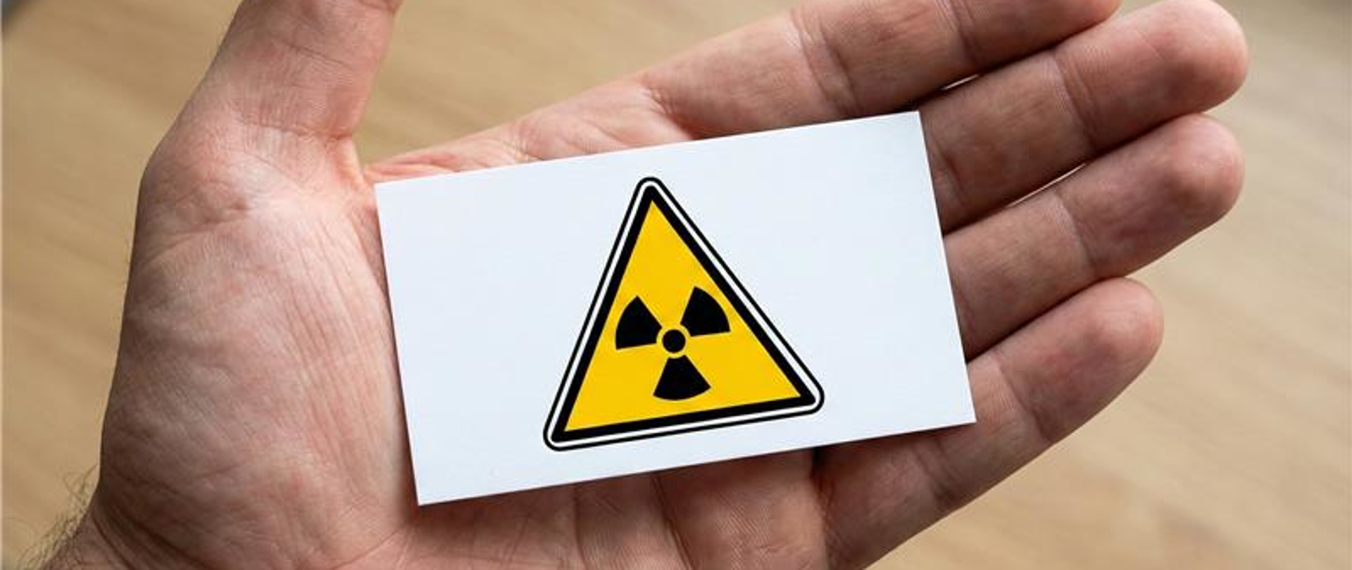 Na dłoni kwadratowy znak - symbol promieniowania radioaktywnego