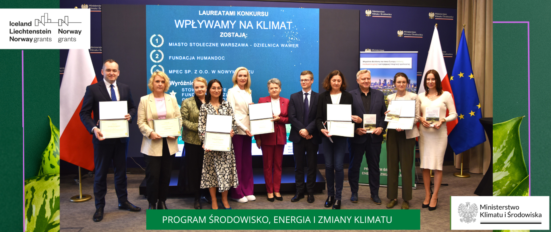 grafika zawiera 11 osób, laureatów konkursu Programu klimatycznego EOG "Wpływamy na klimat" oraz wicedyrektora Departamentu Funduszy Europejskich. Osoby stoją na tle ścianki z logotypami MKIŚ i ekranu wyświetlającego wyniki konkursu. Po stronie lewej i prawej flagi Polski i Unie Europejskiej. Na dole nazwa programu. W górnym lewym rogu, logotyp NMF I MF EOG. W dolnym prawym rogu logotym MKIŚ. 