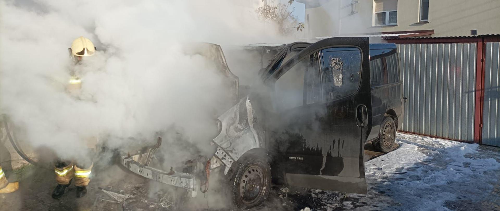 Dzień. Duże zadymienie, strażacy gaszący busa.