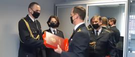 Zdjęcie przedstawia wręczenie przez Komendanta Miejskiego PSP w Białymstoku drobnych upominków okolicznościowych