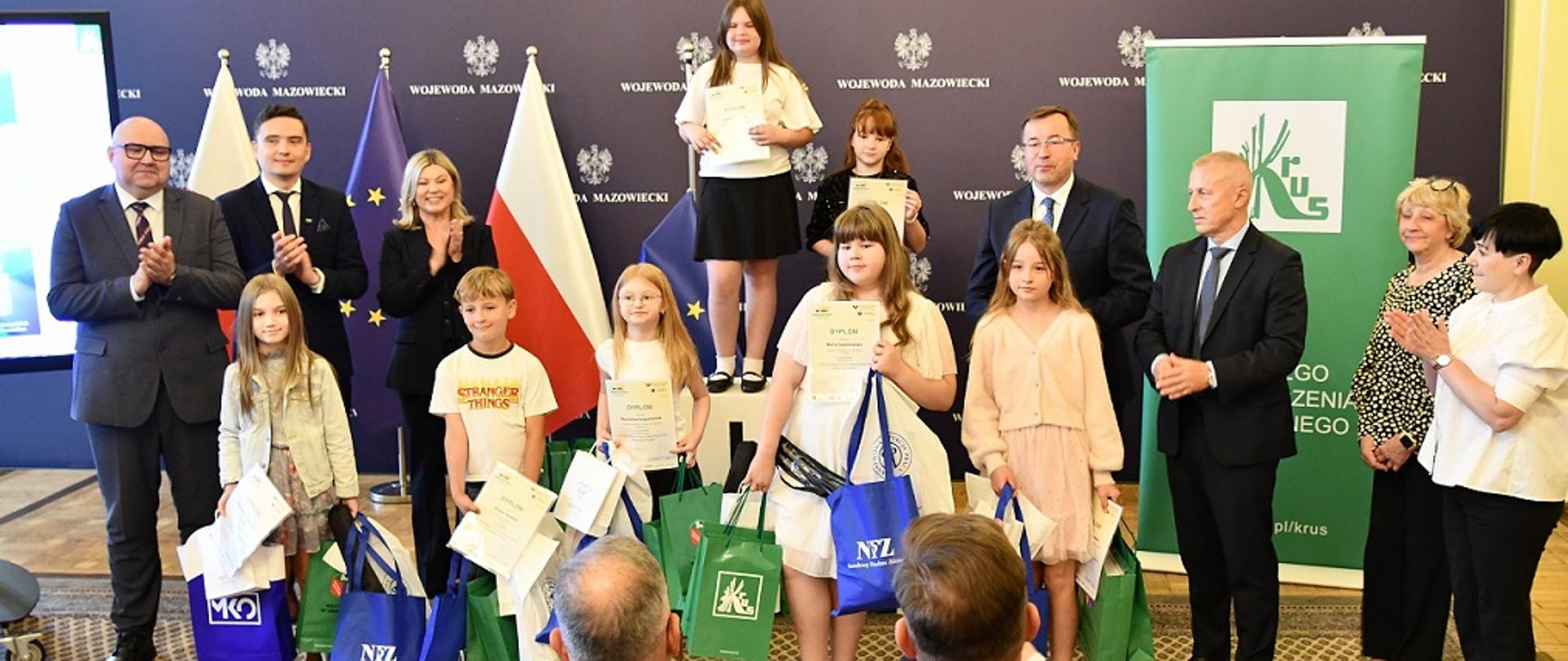 Laureaci konkursu plastycznego z podarkami, a wokoło laureatów przedstawiciele instytucji