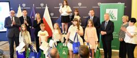 Laureaci konkursu plastycznego z podarkami, a wokoło laureatów przedstawiciele instytucji