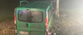 Zdjęcie przestawia tył uszkodzonego samochodu koloru zielonego dostawczego Opla VIVARO po uderzeniu w przydrożne drzewo. Oświetlone miejsce wypadku z uwagi na godzinę poranną. W prawej części zdjęcia znajdują się wycięte przy użyciu narzędzi hydraulicznych drzwi pojazdu. 