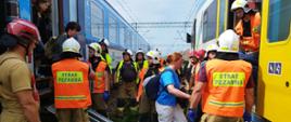 Strażacy pomagają w bezpiecznym opuszczeniu pociągu przez pasażerów, który uległ awarii, kierują ich do rezerwowego składu