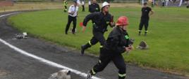 XI Powiatowe Zawody Sportowo-Pożarnicze OSP i MDP. Stadion w Miejskiej Górce. Na bieżni rozgrwana jest sztafeta pożarnicza 7x50 m z przeszkodami. Zawodnicy pokonują pierwszy odcinek toru. Za nimi ustawione są rozdzielacze i wąż tłoczny.